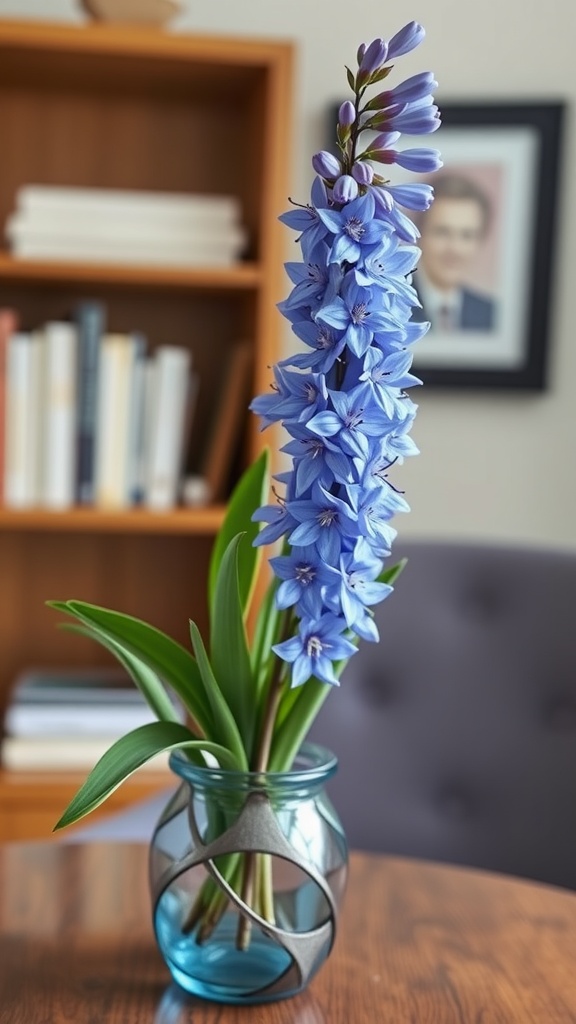 A vase of tall blue larkspur flowers on a wooden table in a home office setting.